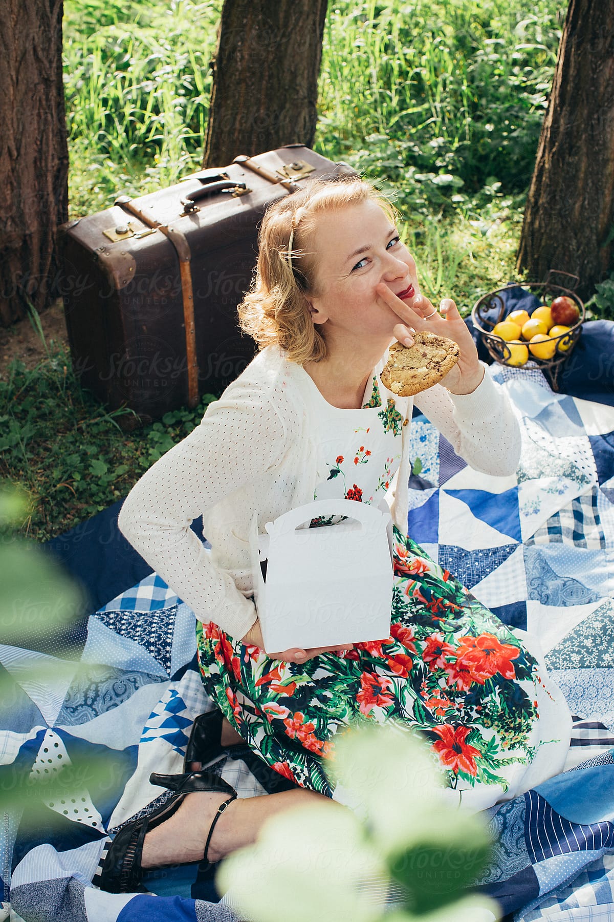 Summer Picnic - Pretty Blond Woman Enjoying Eating A Big Cookie in Sunny Meadow