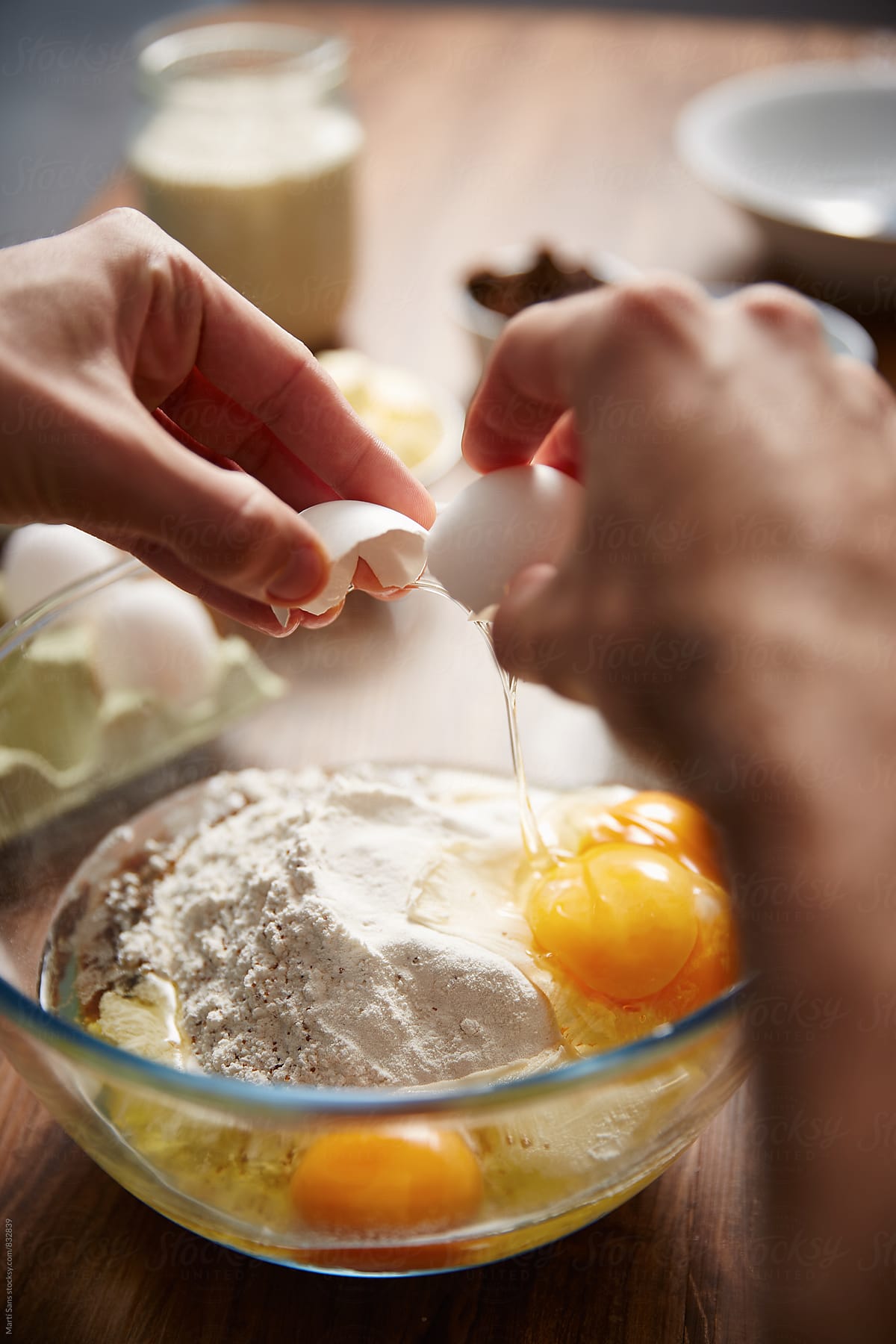Close-up of hands adding eggs in bowl, making panettone