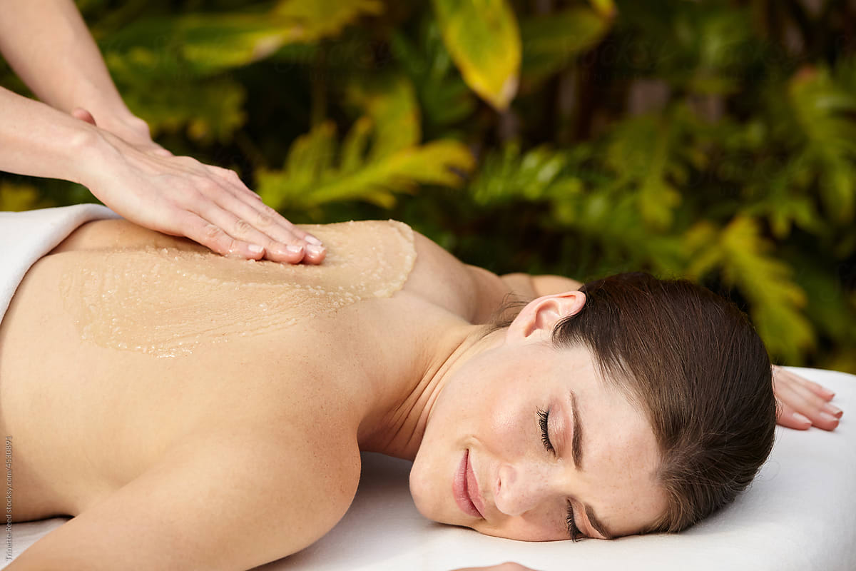 Close-up of woman receiving an exfoliating salt scrub massage at spa