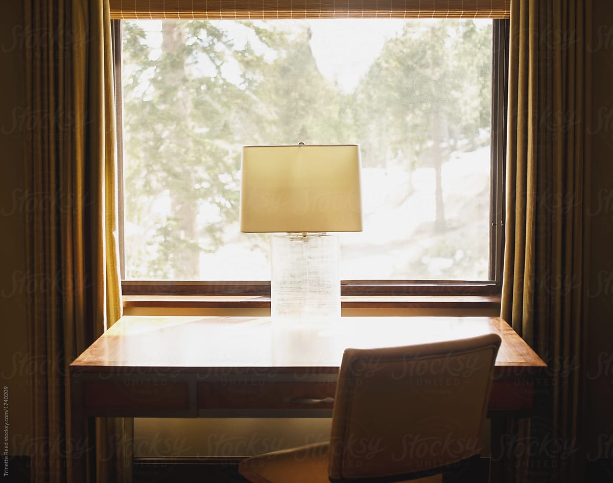 Desk and lamp in front of a window