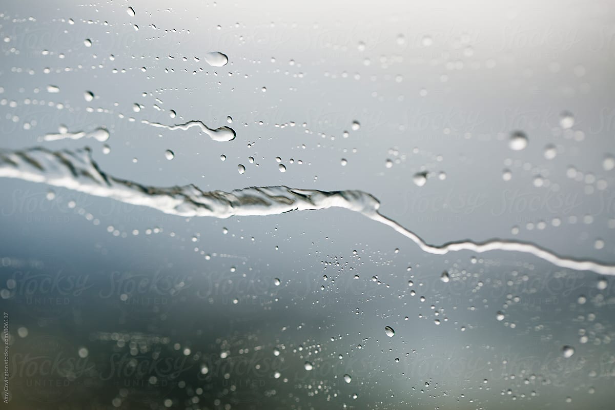 Close up of raindrops moving along a car window