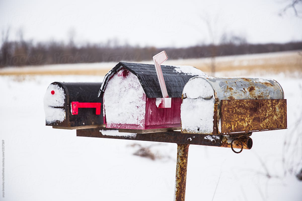 Three snow covered, worn and textured mailboxes