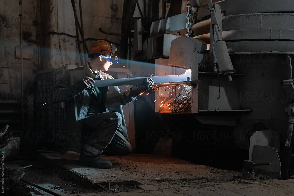 Worker putting metal in furnace