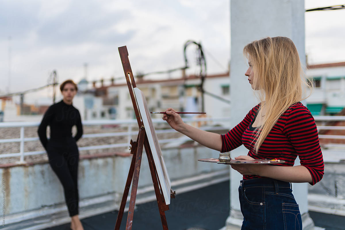 An artist painting a model on rooftop