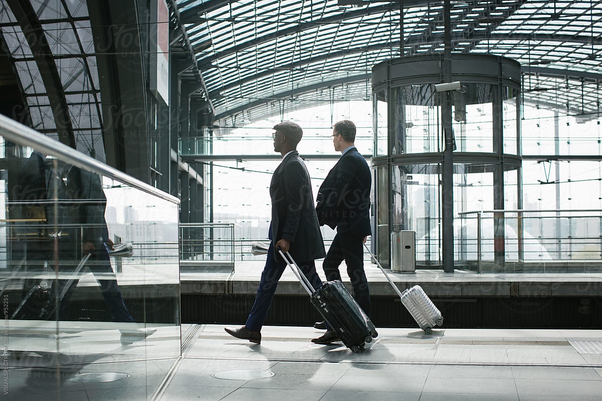 Two Business Travelers Walking With Carry On Suitcases in Modern Train Station