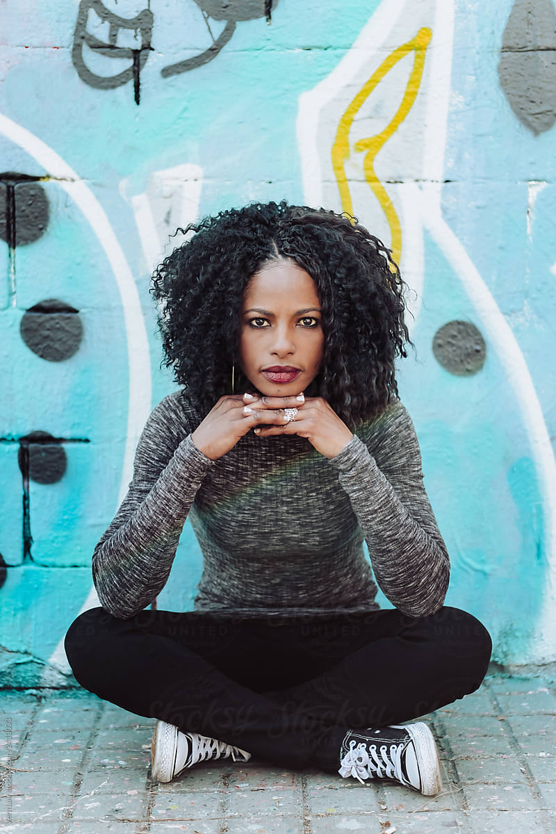 Beautiful Afro Woman sitting in front a blue wall