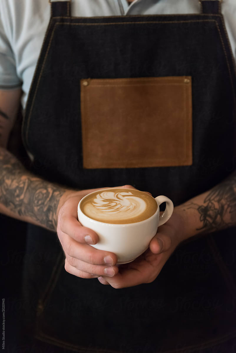 Crop bartender holding cup of latte