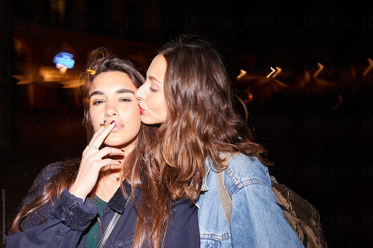 Friend kissing girl smoking cigarette.