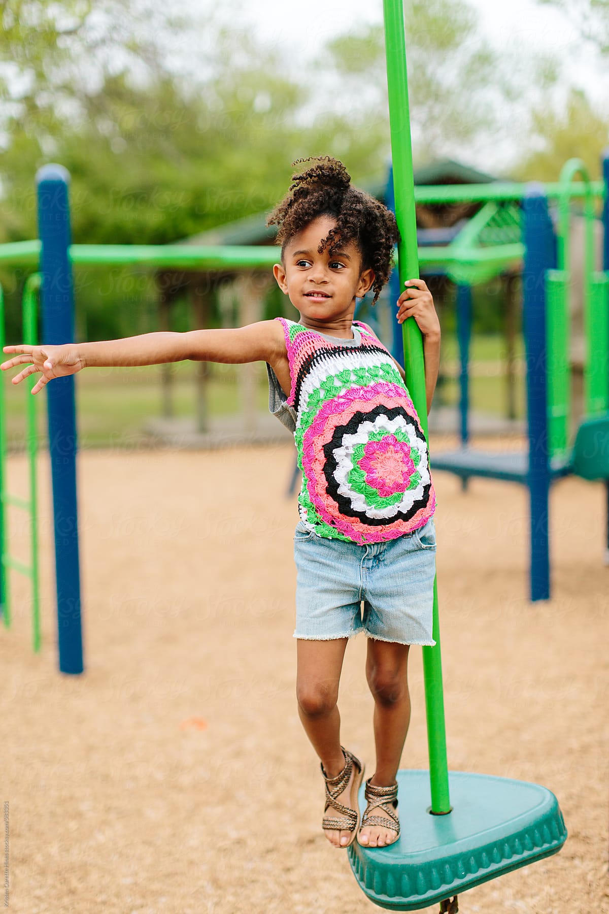 A Little Girl Sliding Down A Green Slide At The Playground. by Stocksy  Contributor Kristen Curette & Daemaine Hines - Stocksy