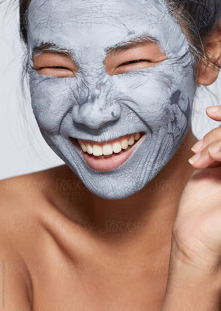 Asian woman smiling with mud mask on