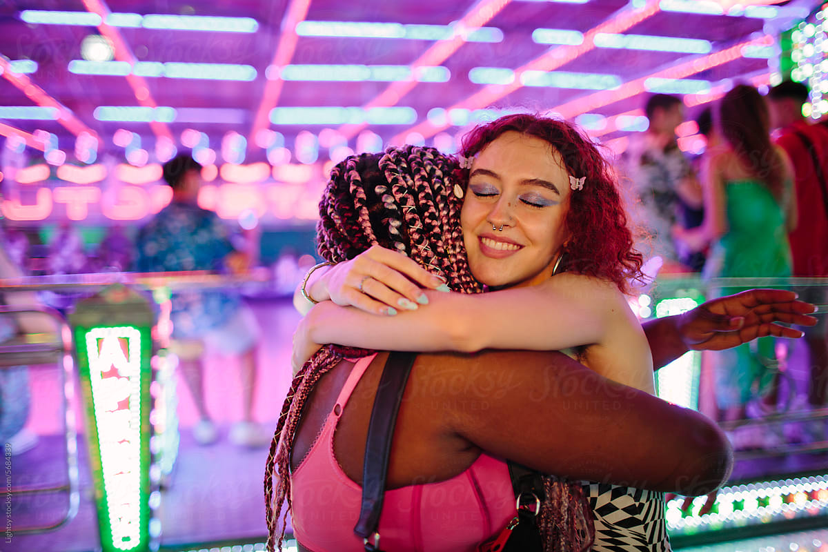 Women hugging each other at a fair at night