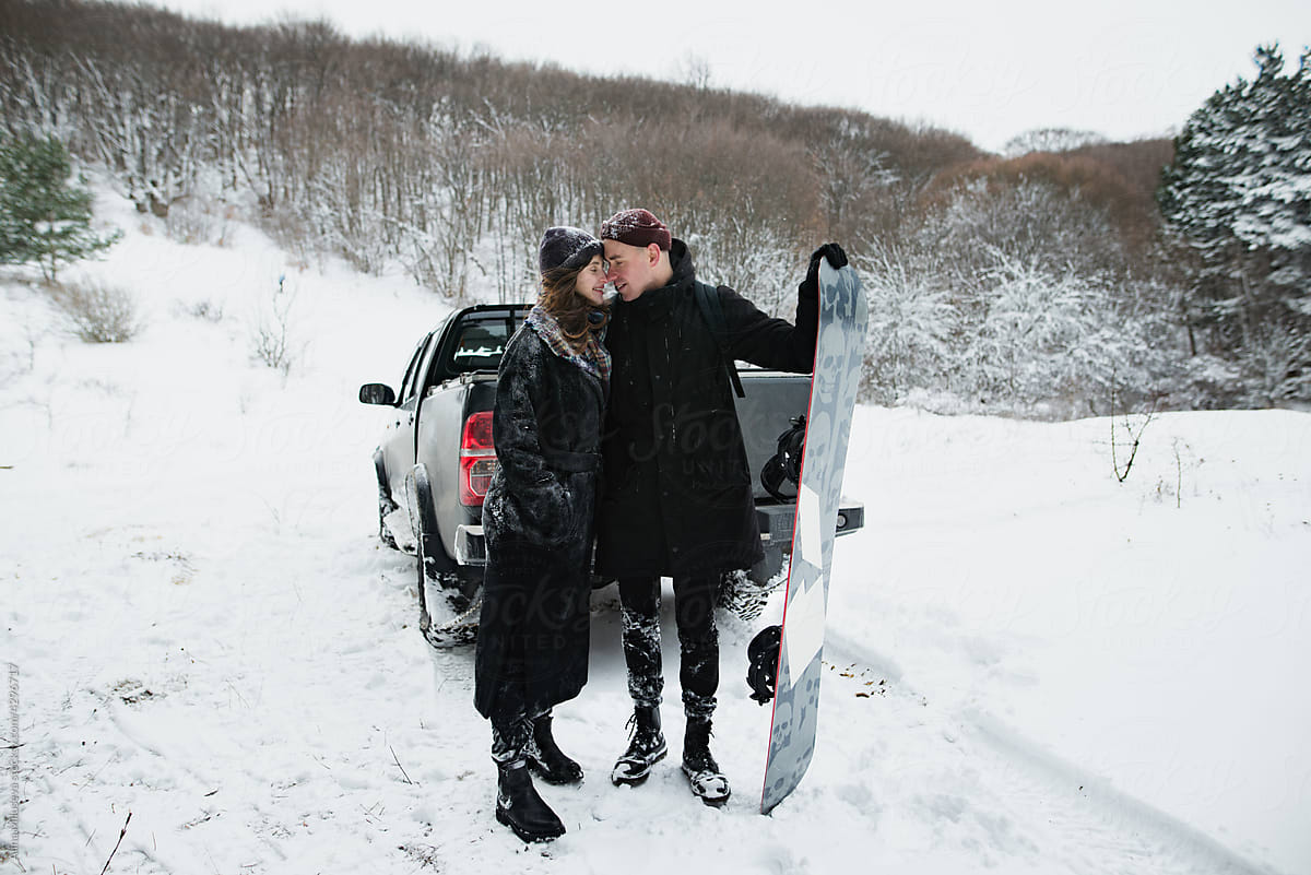 Happy couple with a snowboard in the winter