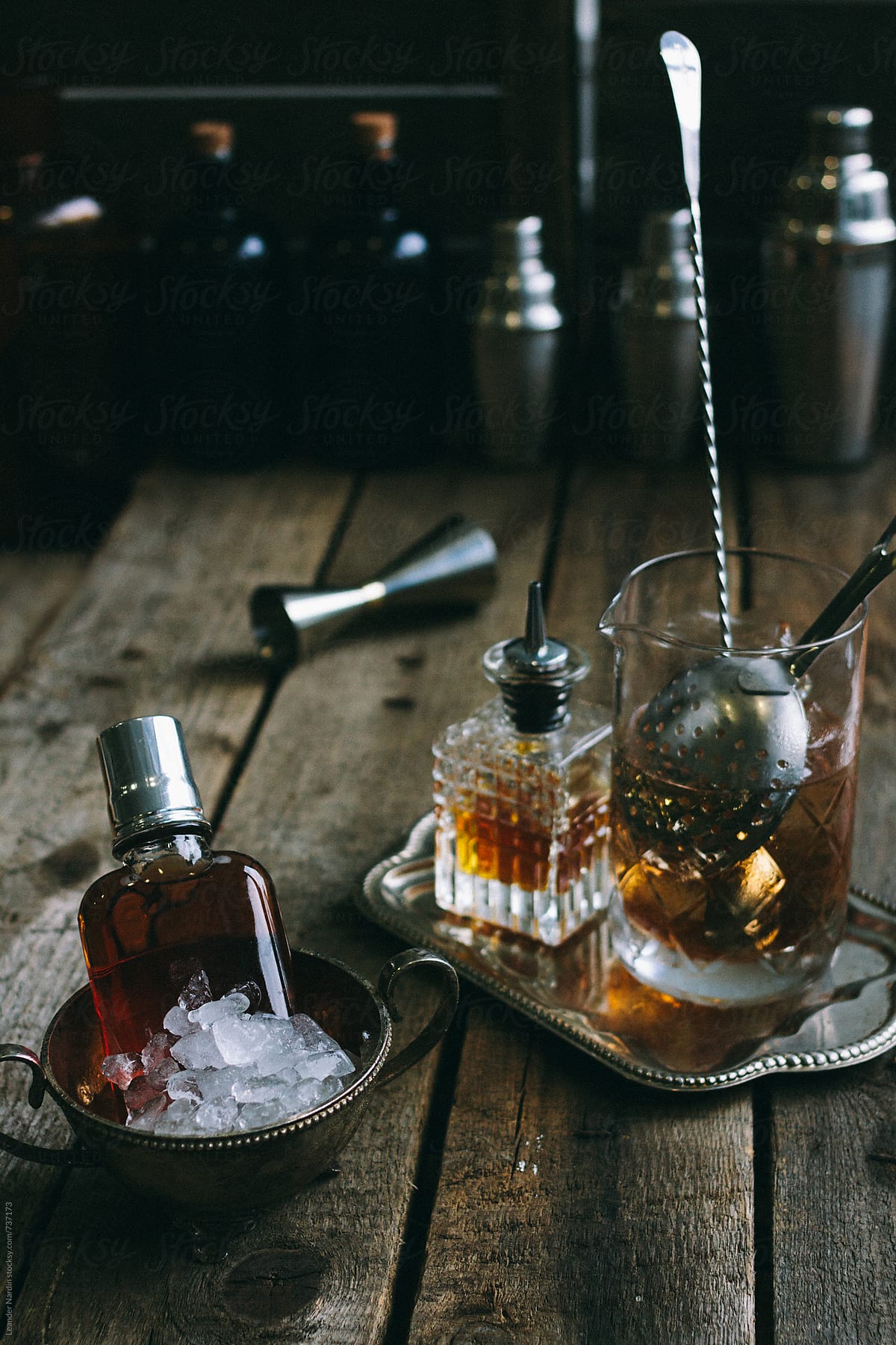 classic manhattan cocktail ingredients in a mixing tumbler served in a flask on wooden background
