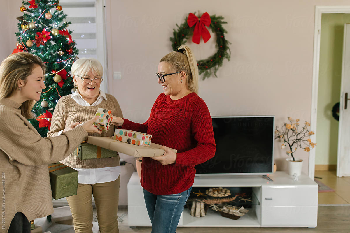 Smiling women exchanging Christmas presents at home