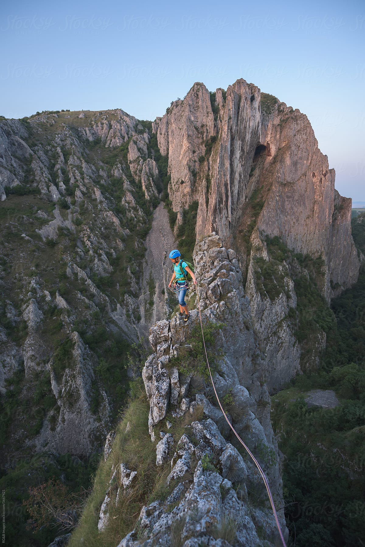 Female rock climber standing on top of a narrow ridge