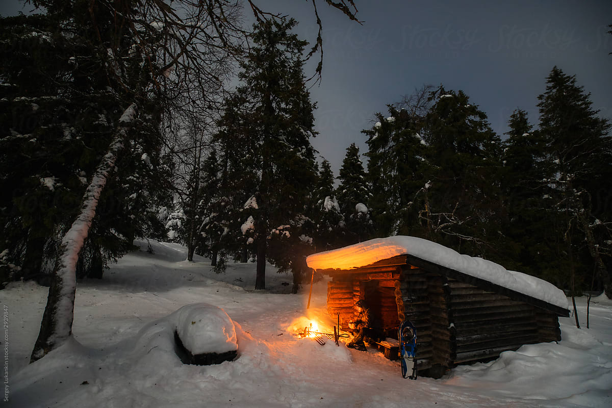 A man sits in the night winter forest near the fire