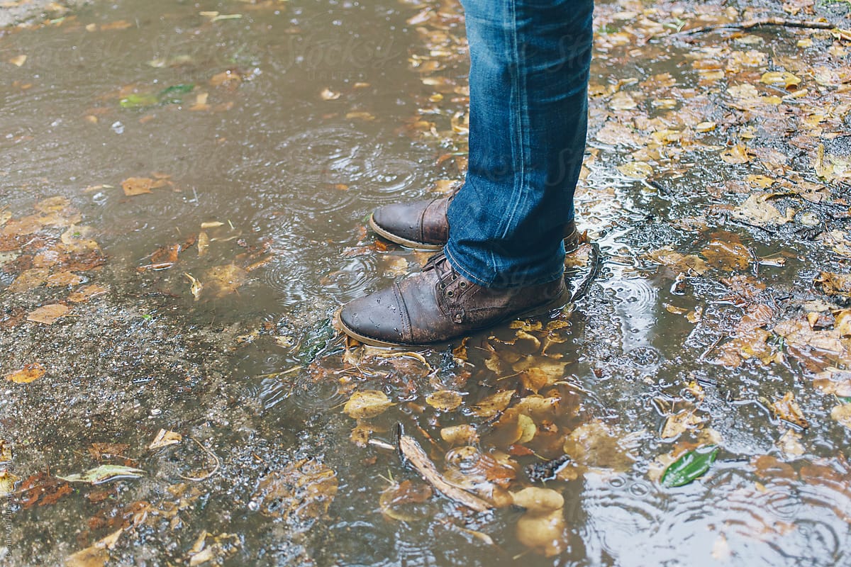 Leather boots in a brown puddle of rainwater.