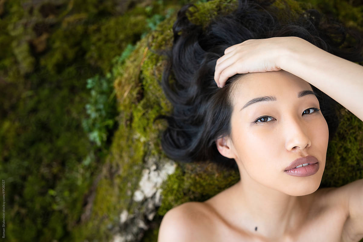 Attractive Asian woman lying on rocky surface