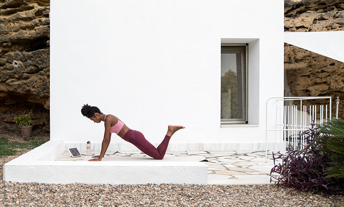 Ethnic woman stretching in Yoga pose on porch