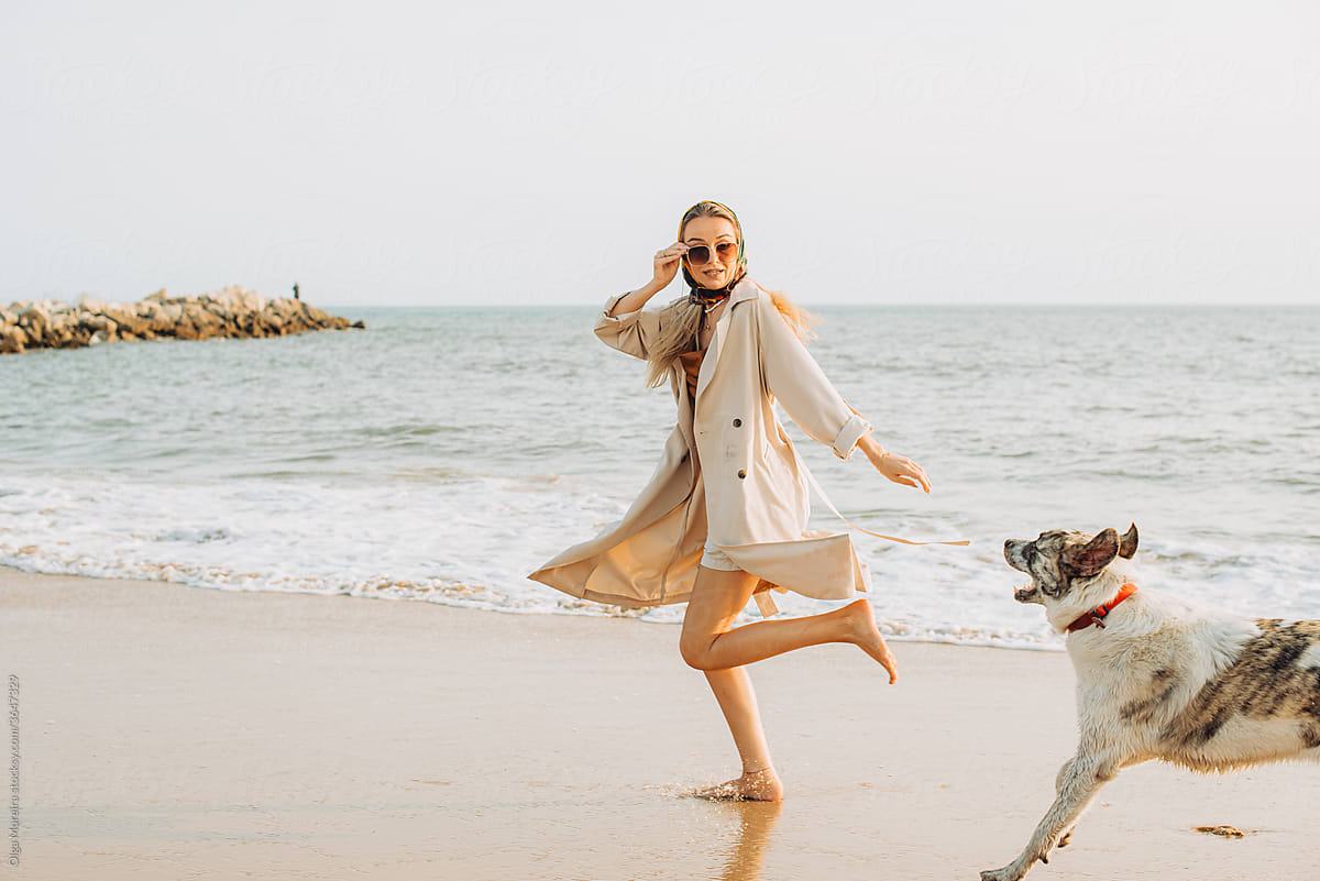 Dog running after a young woman by the sea