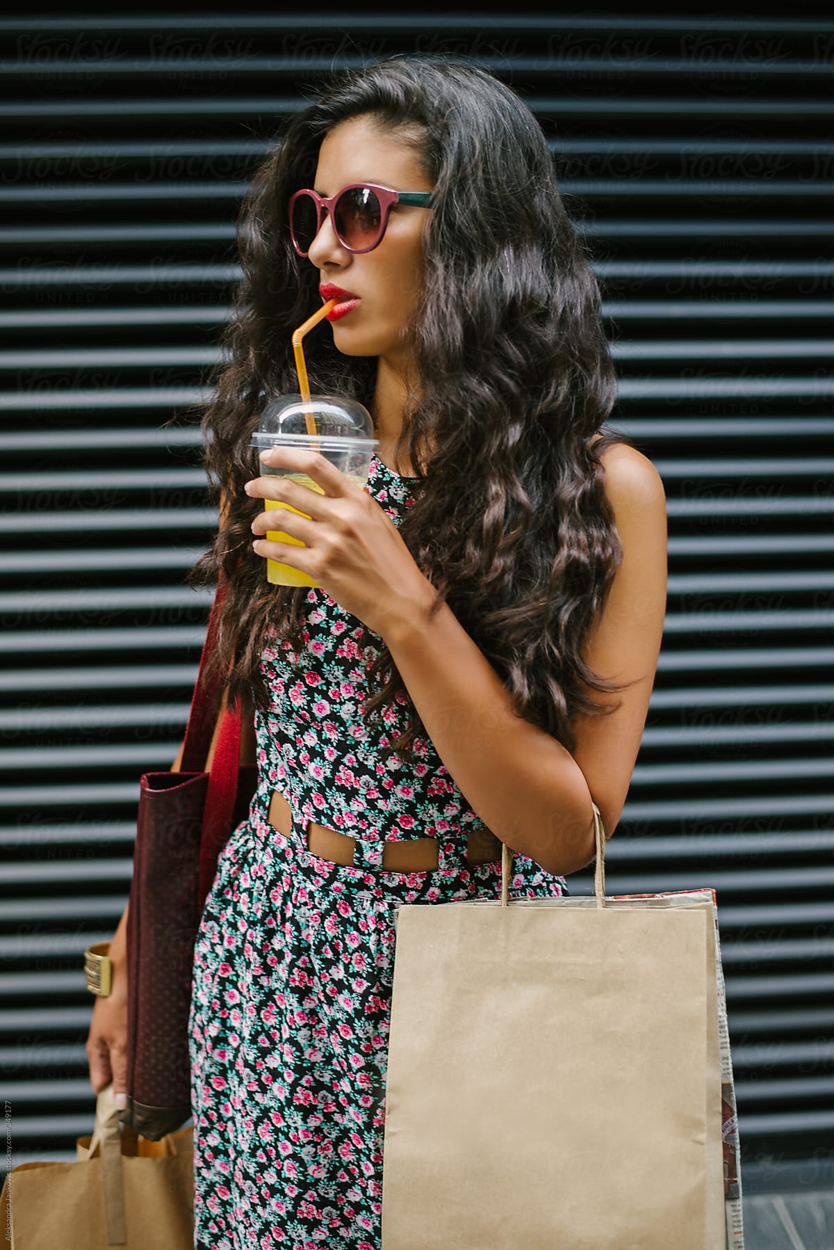 Young Brunette Woman with Shopping Bags Drinking Juice On The Street