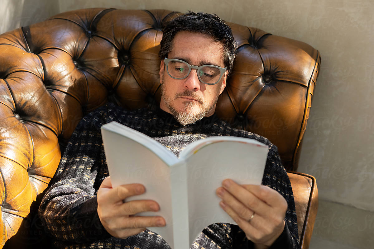 mature man reading a book on sofa