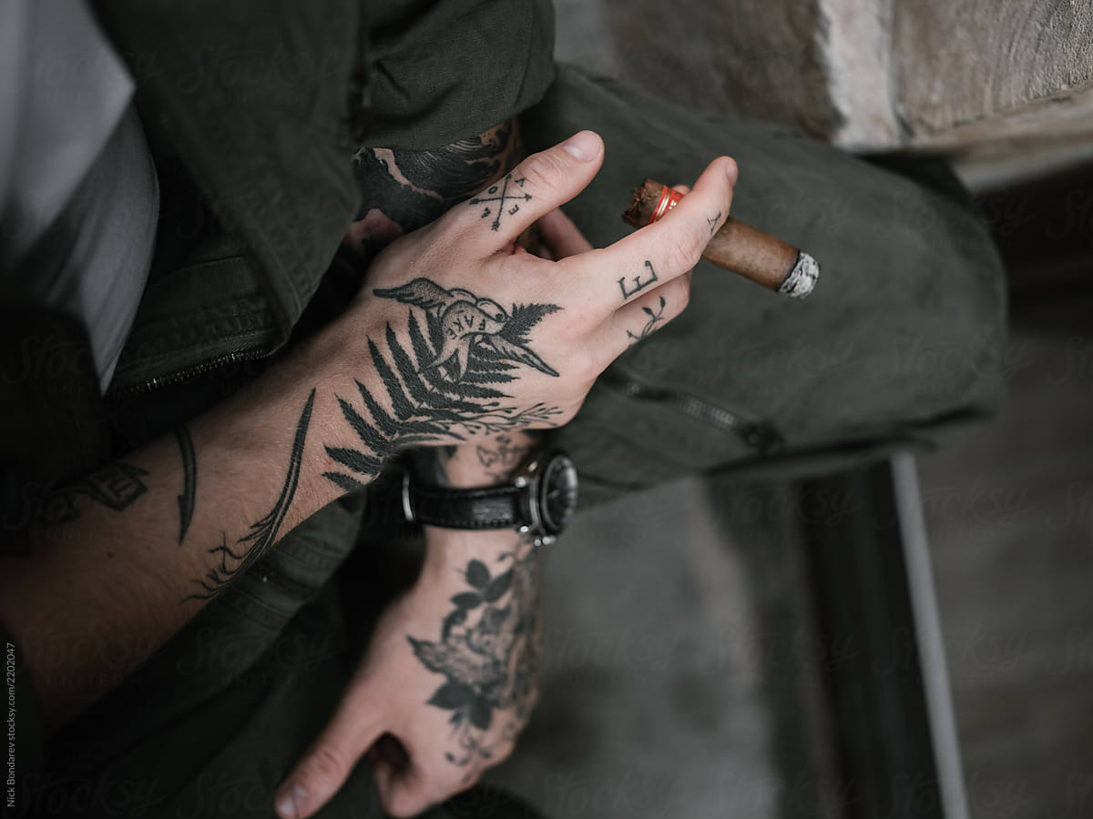 Handsome tattooed man lighting cigar