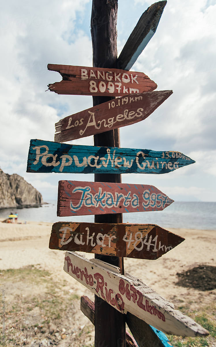 Travel destinations on wooden colorful sign at a beach