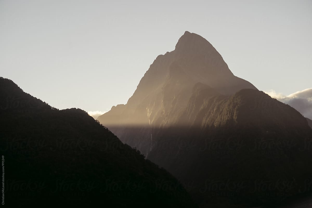 Milford Sound cliff being wrapped by sun rays in the evening.