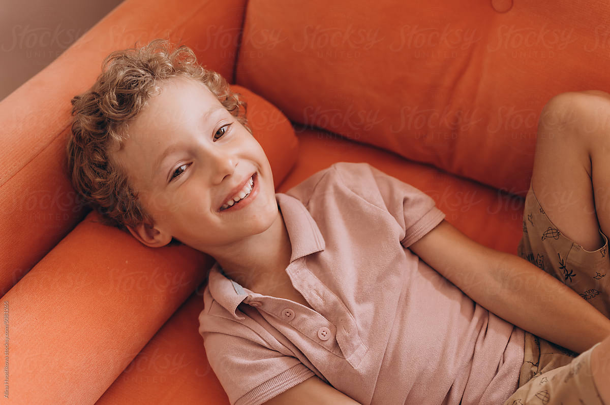 Cheerful boy lying on sofa at home