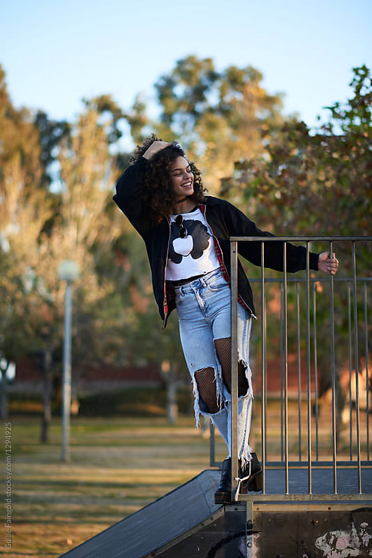 Stylish girl in ripped jeans in park.
