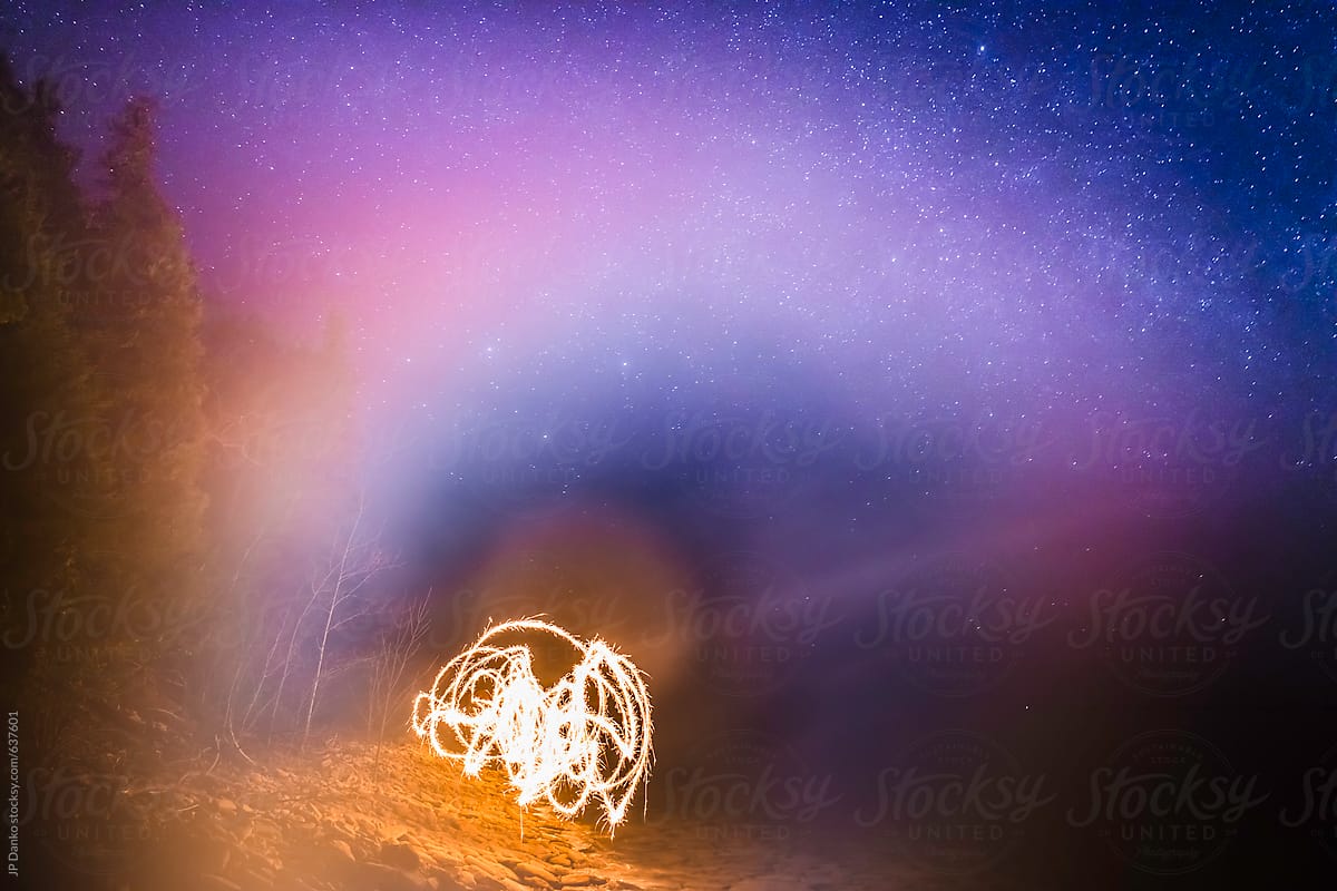 Woman Waving Sparklers on Wilderness Beach on Foggy Night with Milkyway Stars