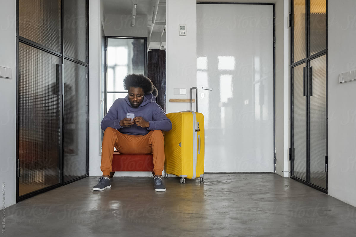 Black traveler using smartphone in corridor