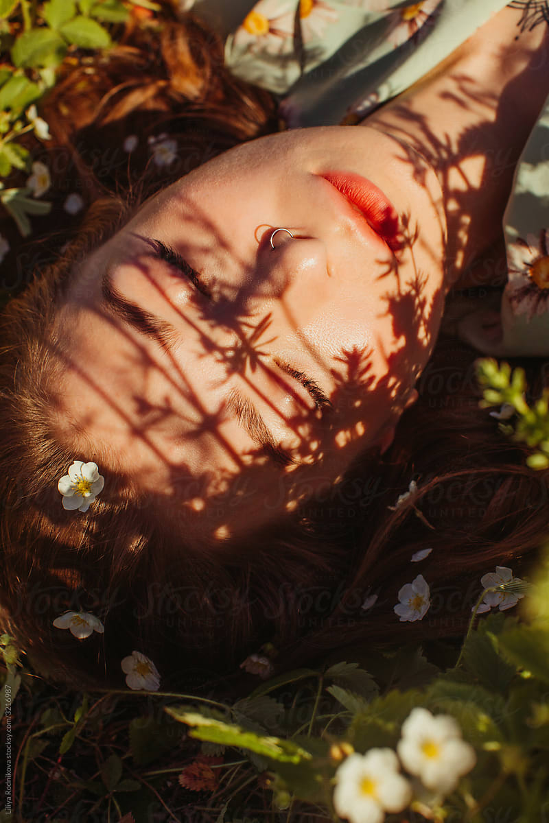 Dreamy portrait of model among flowers and shadows