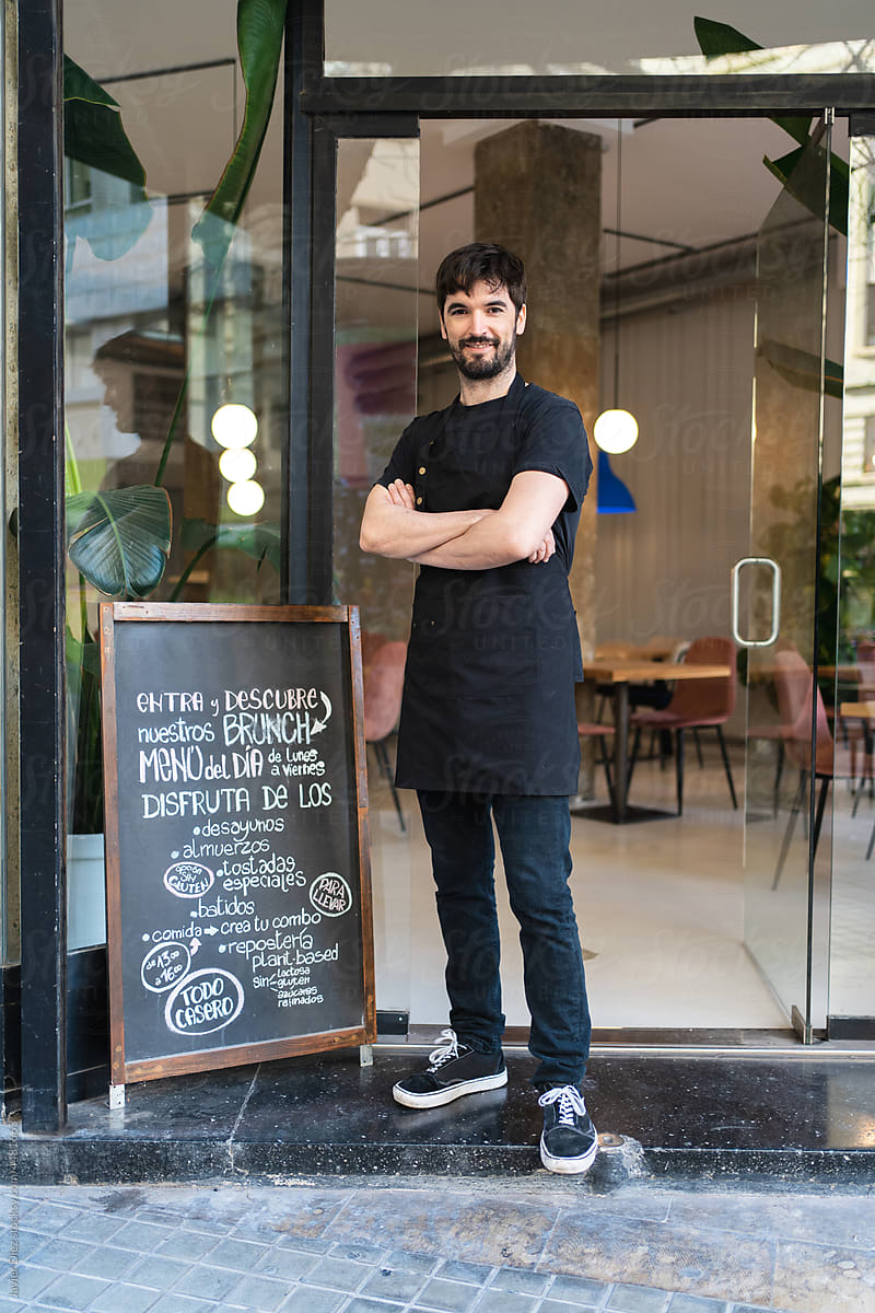 Smiling entrepreneur standing in cafe entrance