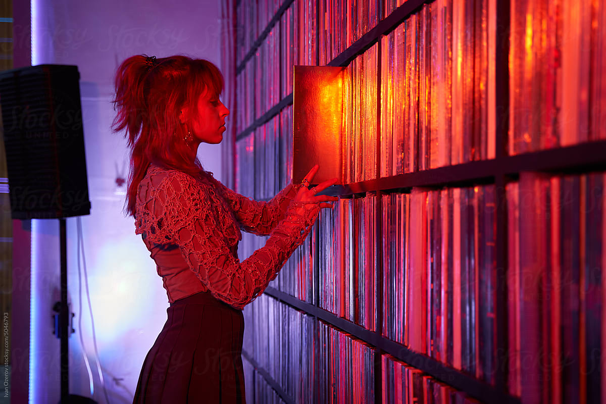 Woman choosing vinyl discs from shelf in shop