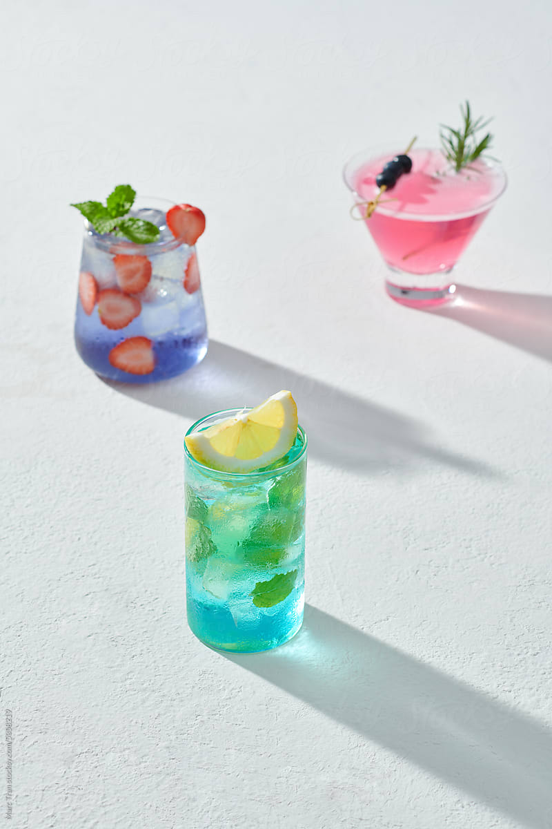 Three colorful summer cocktails in glasses on white table