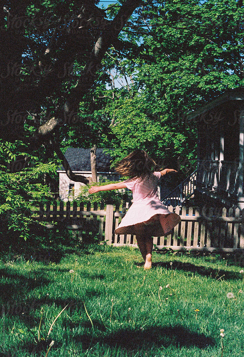 Child Plays and Spins in her Backyard in Springtime