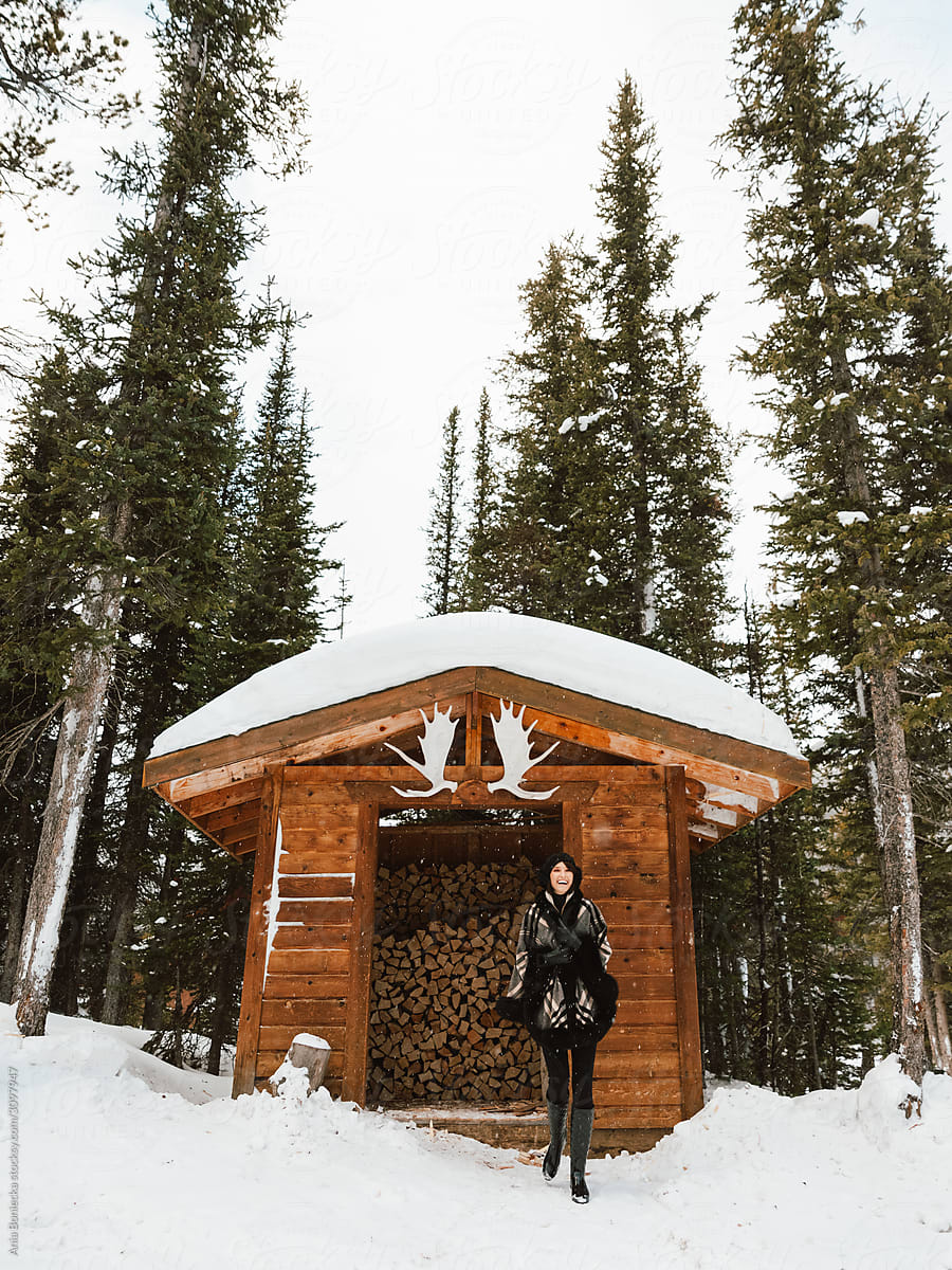 Stylish woman stands in front of firewood shed with antlers.