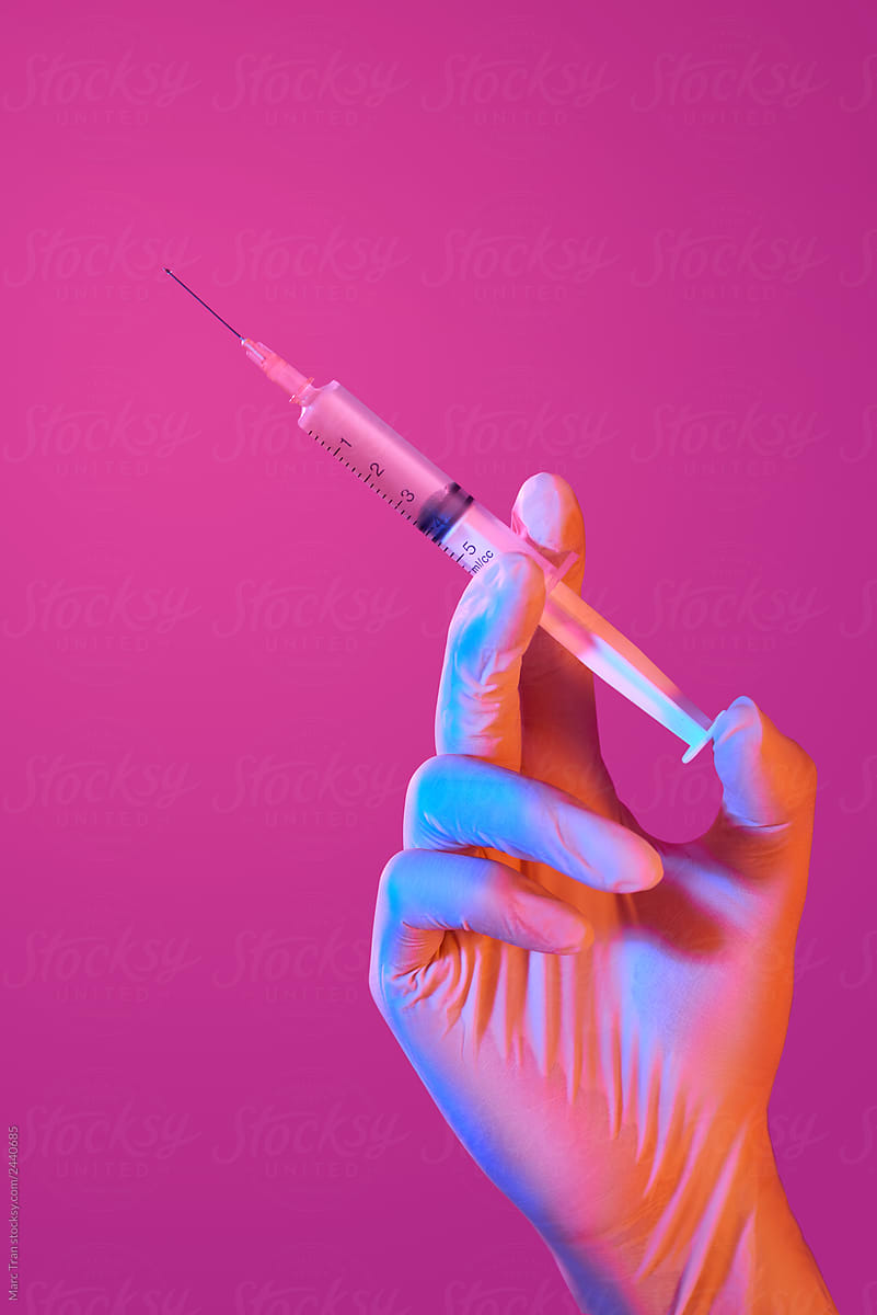 Hand in white glove hold syringe with preparation jet