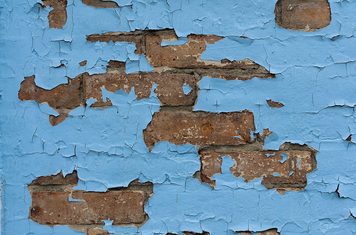 blue paint peeling off an old brick wall
