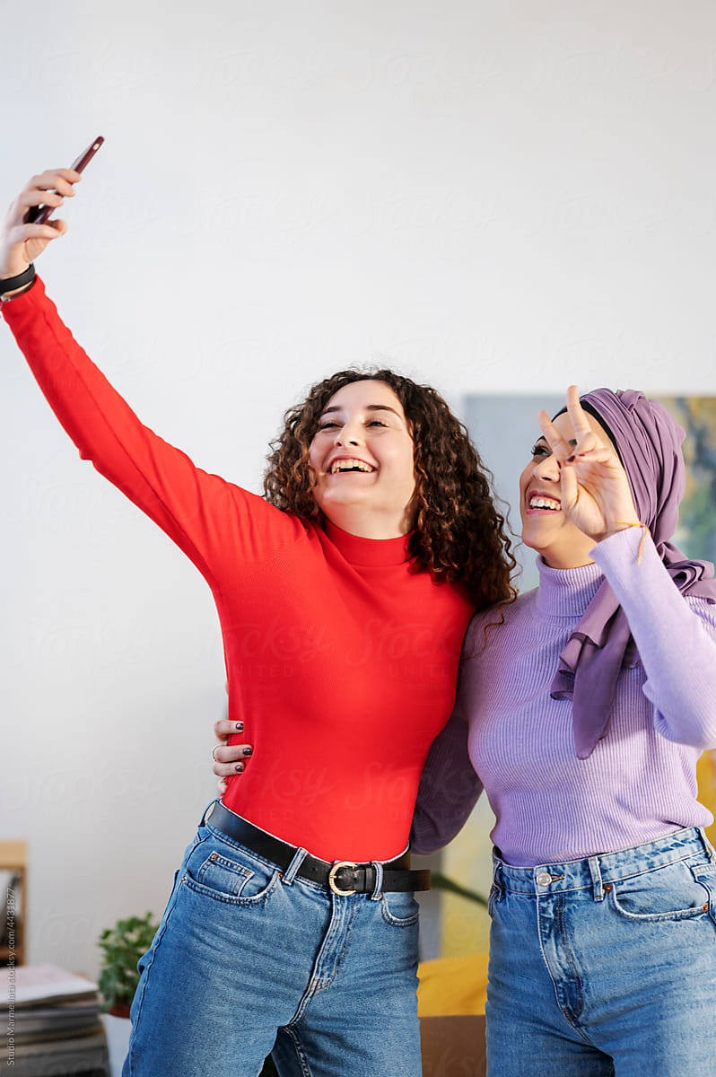 Happy diverse women taking selfie after relocation