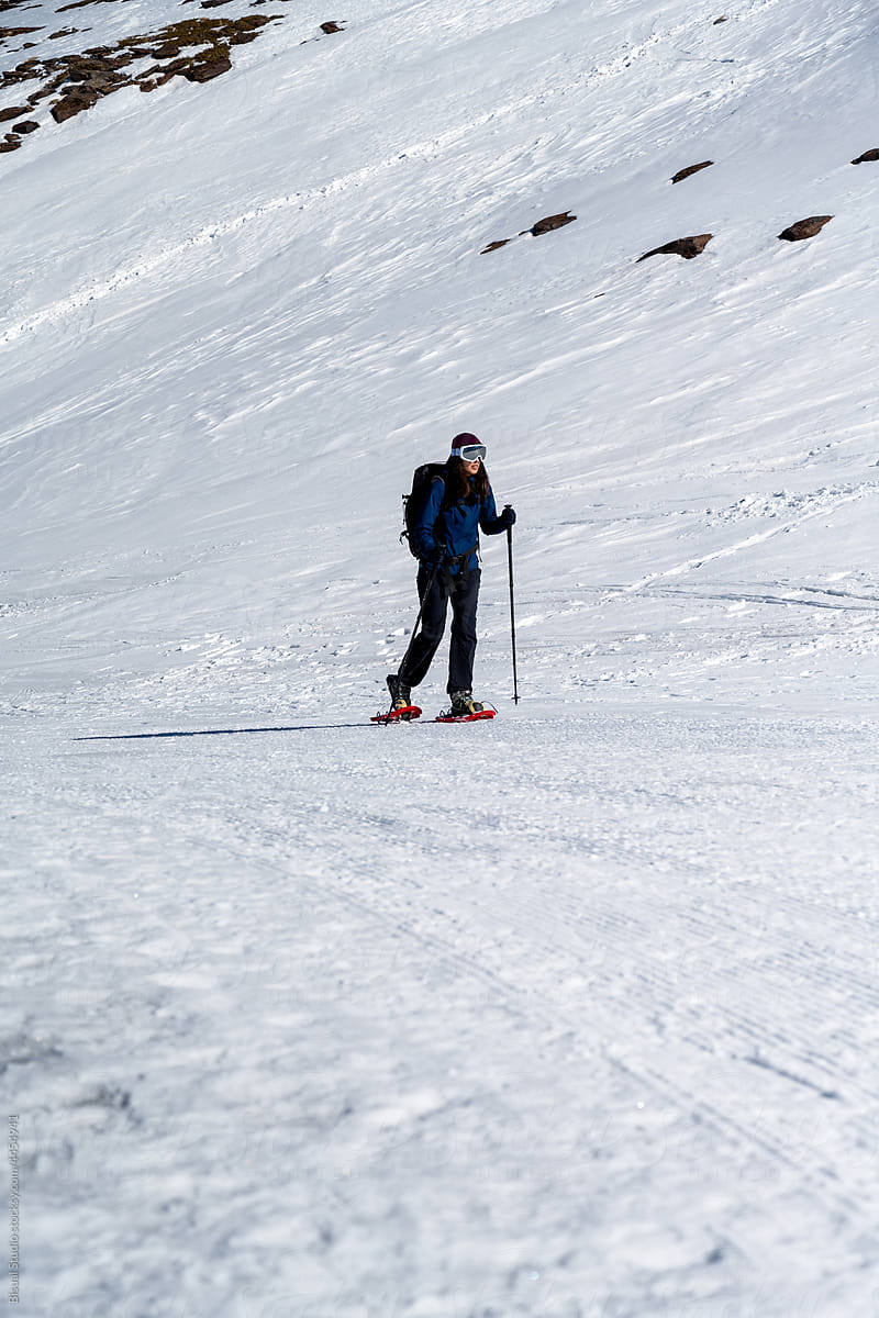 Woman in snowshoes on slope in mountains
