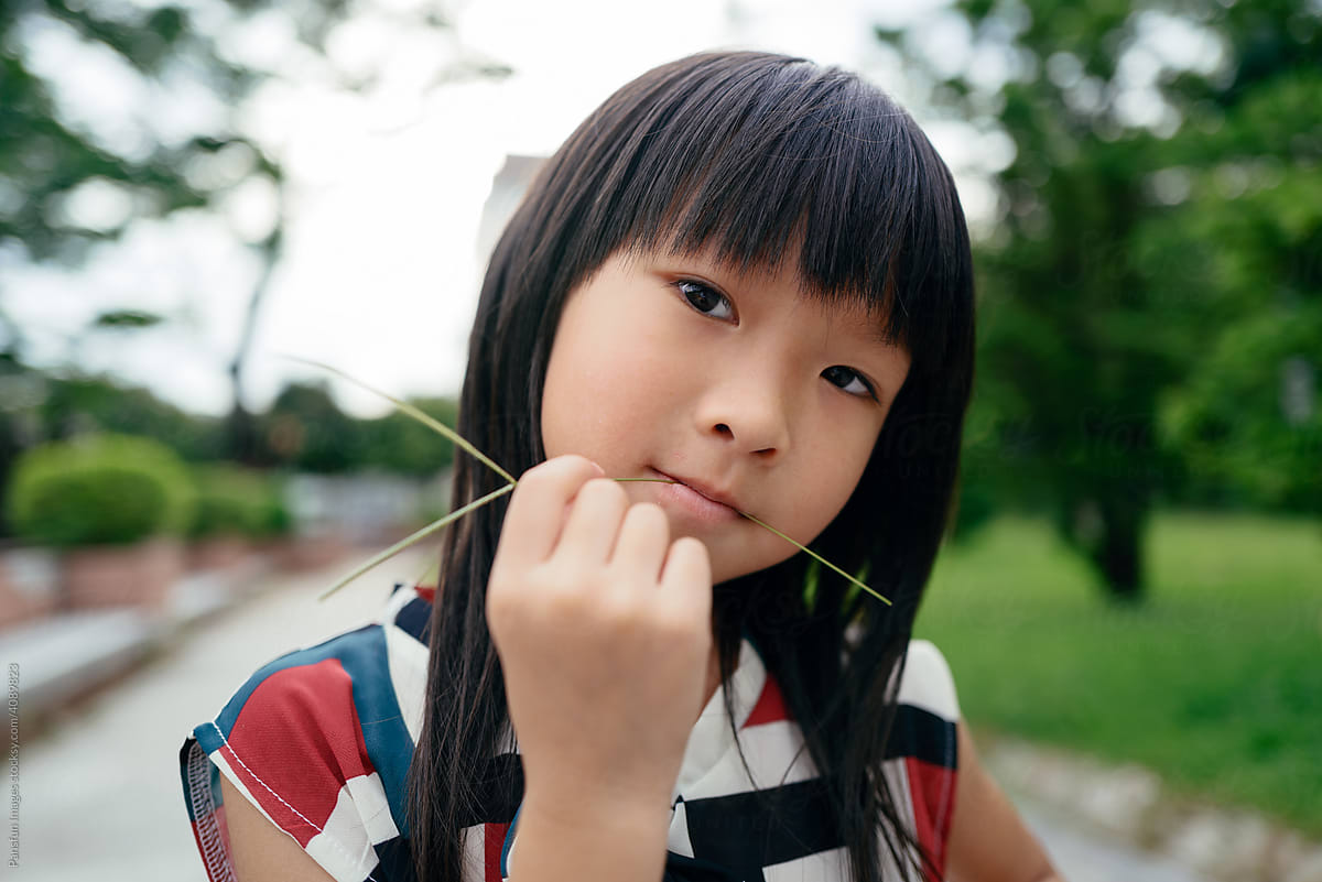 little girl biting a blade of grass