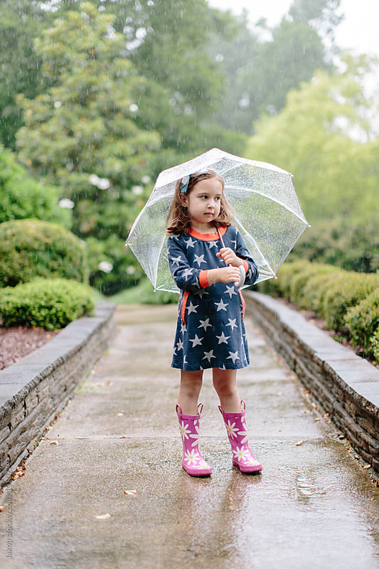 Cute young girl standing in the rain with an umbrella