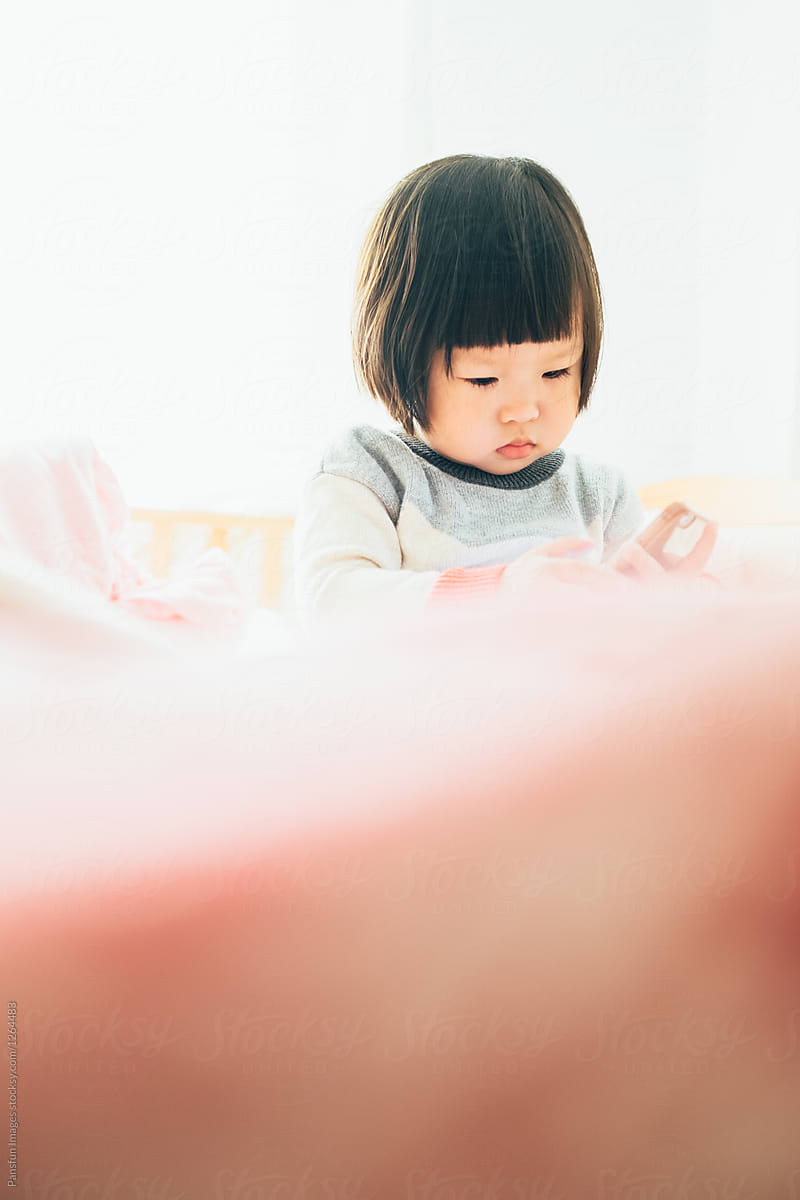 Chinese baby girl on bed with cell phone