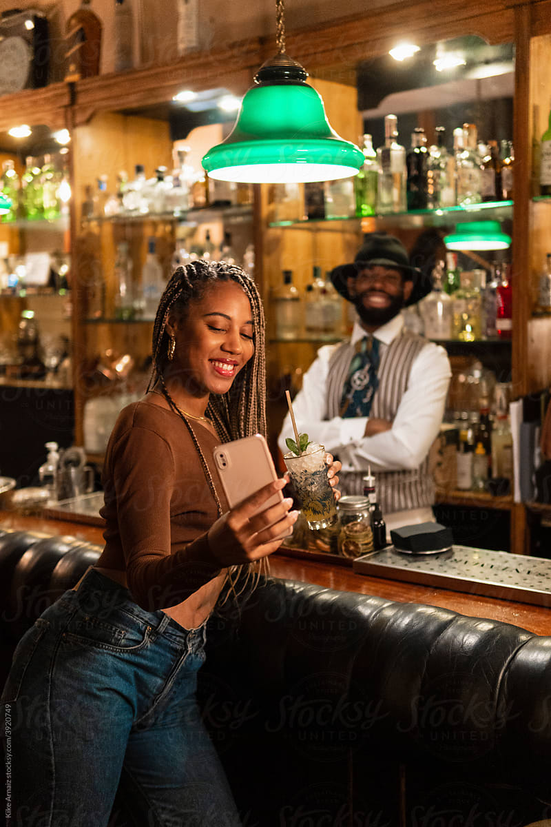 Happy black woman taking selfie with barman
