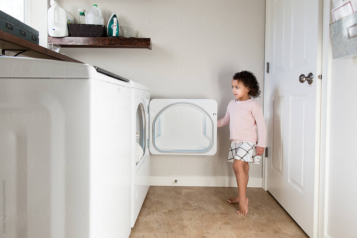 Girl opens dryer in laundry room