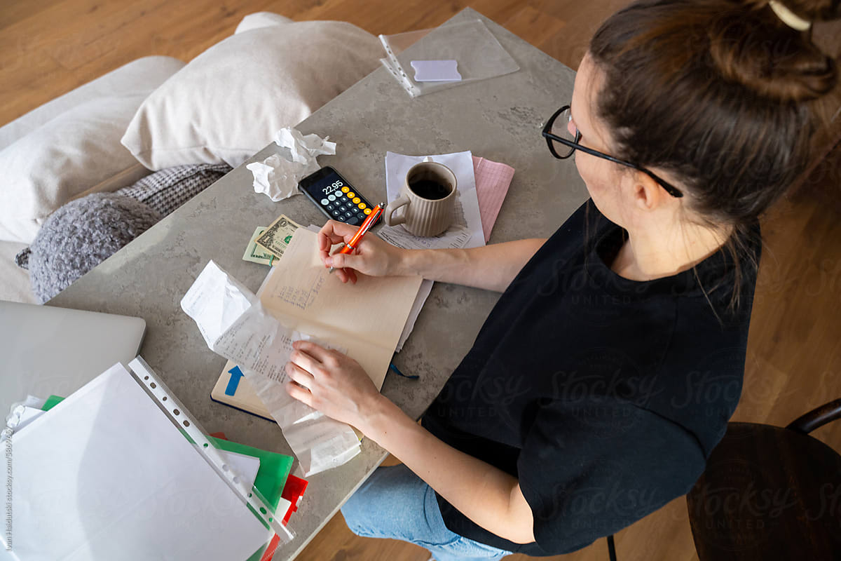 Woman Calculating Expenses while working in Messy Living Room
