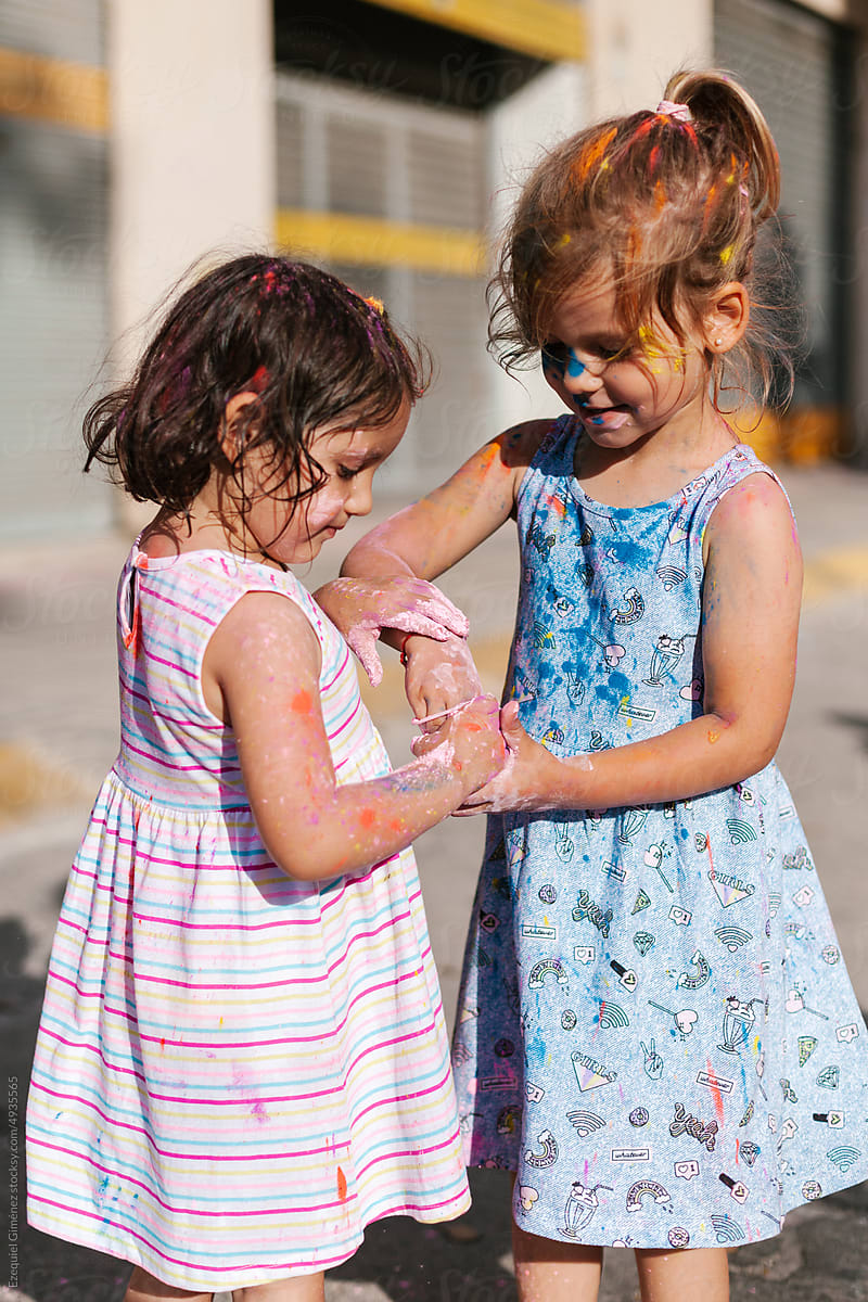 Curious little kids playing with color powder on street